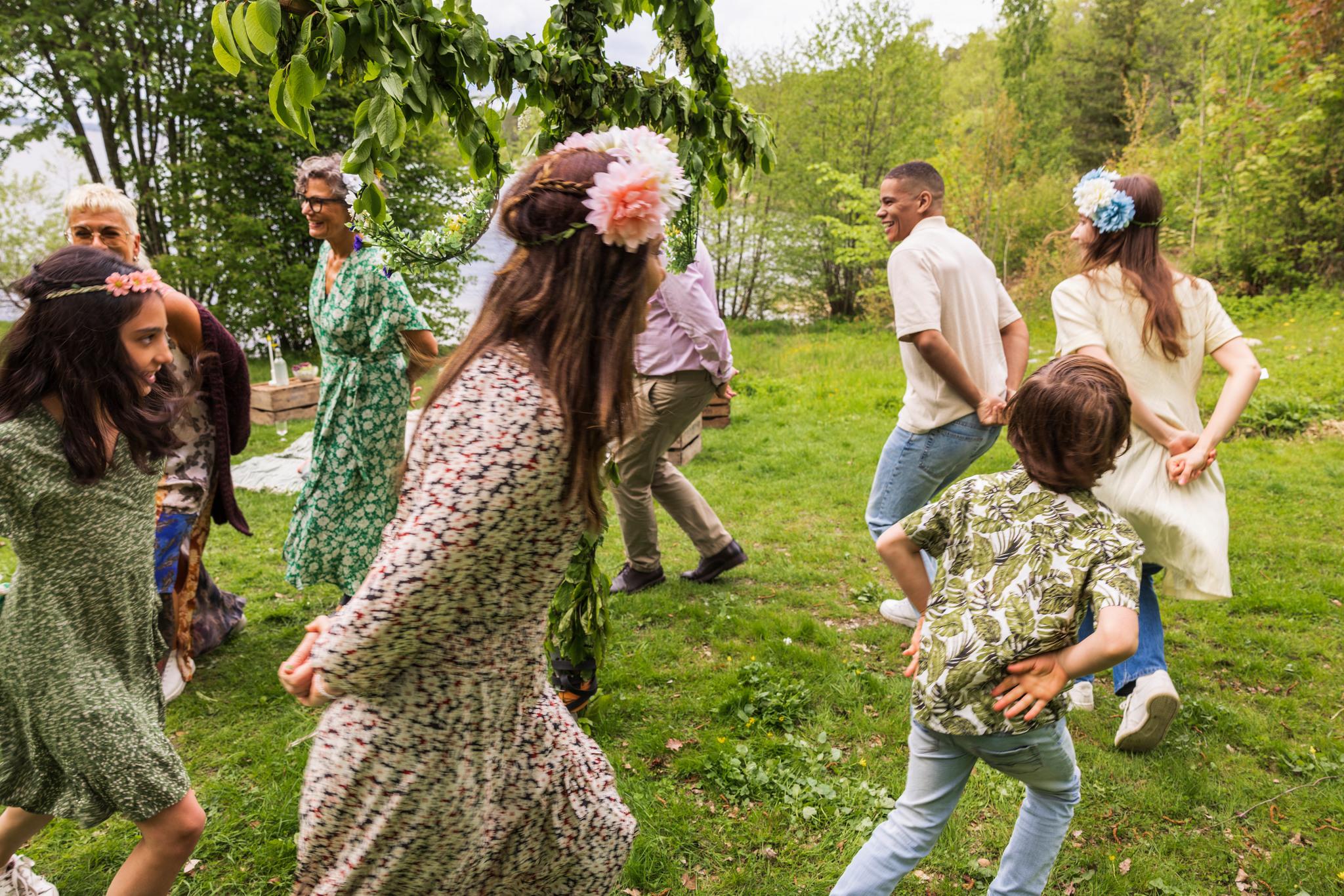 People dancing around a leaf-clad pole.