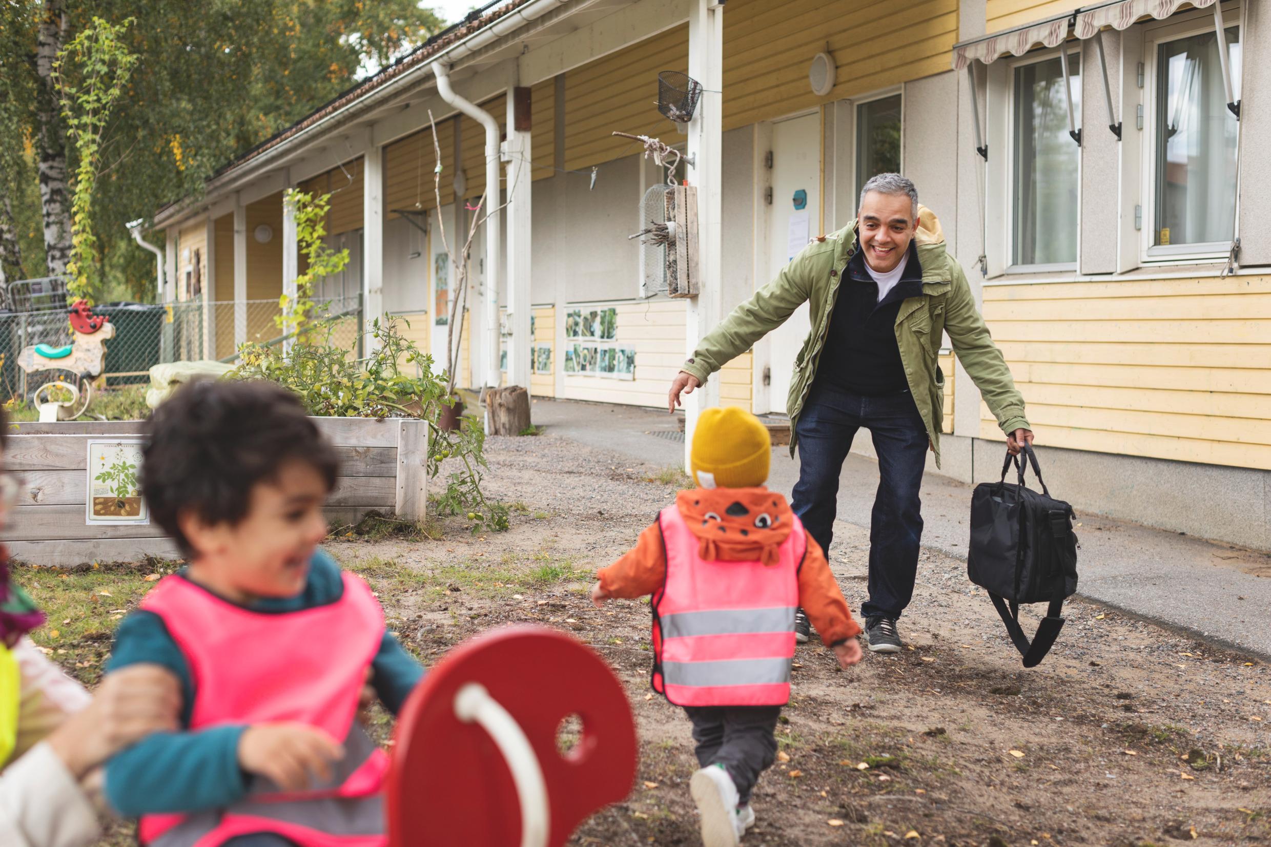 An adult picking up a child at a preschool in a residential area.