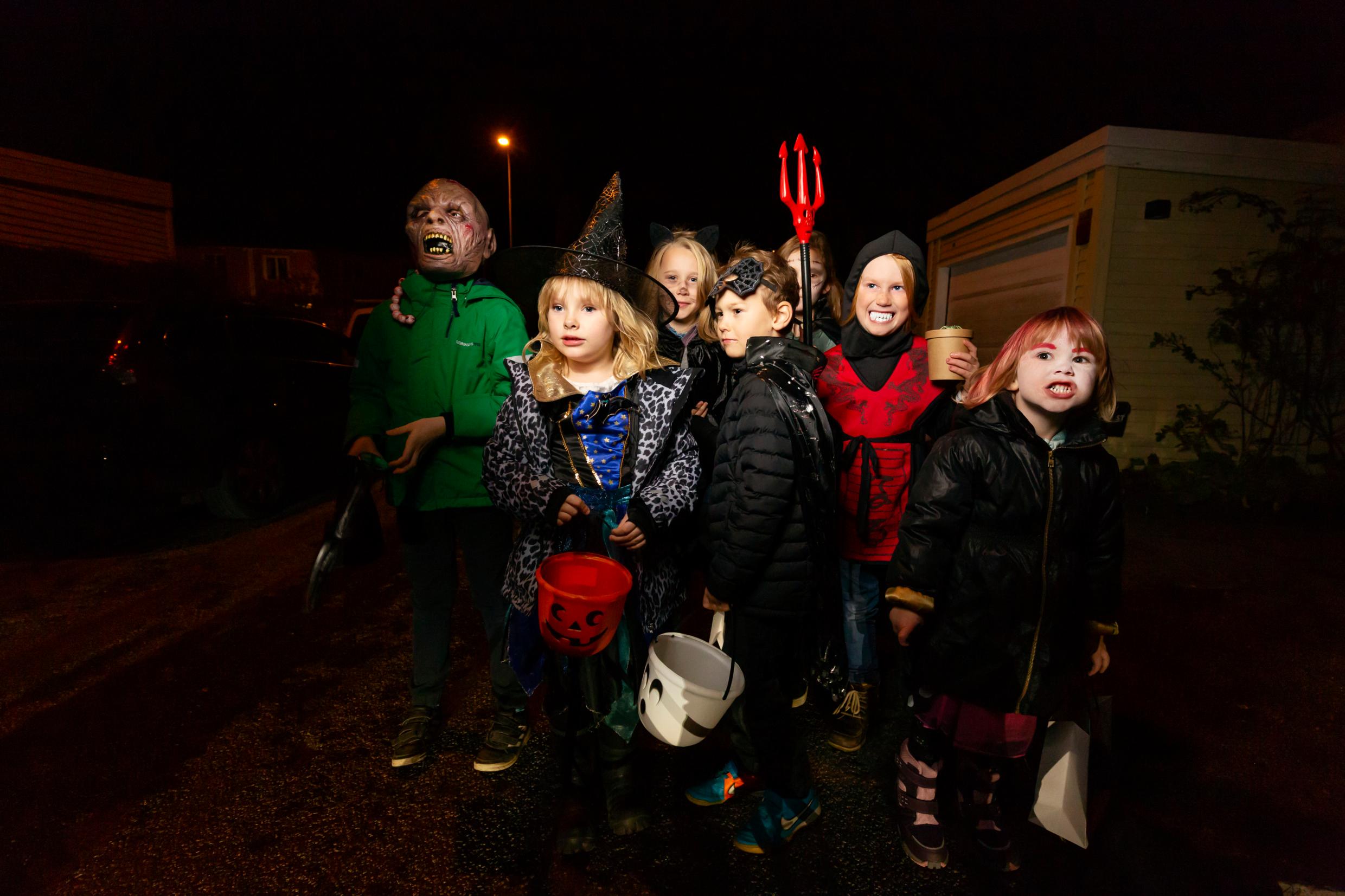 Trick or treat A group of children in costumes walking down a dark street.