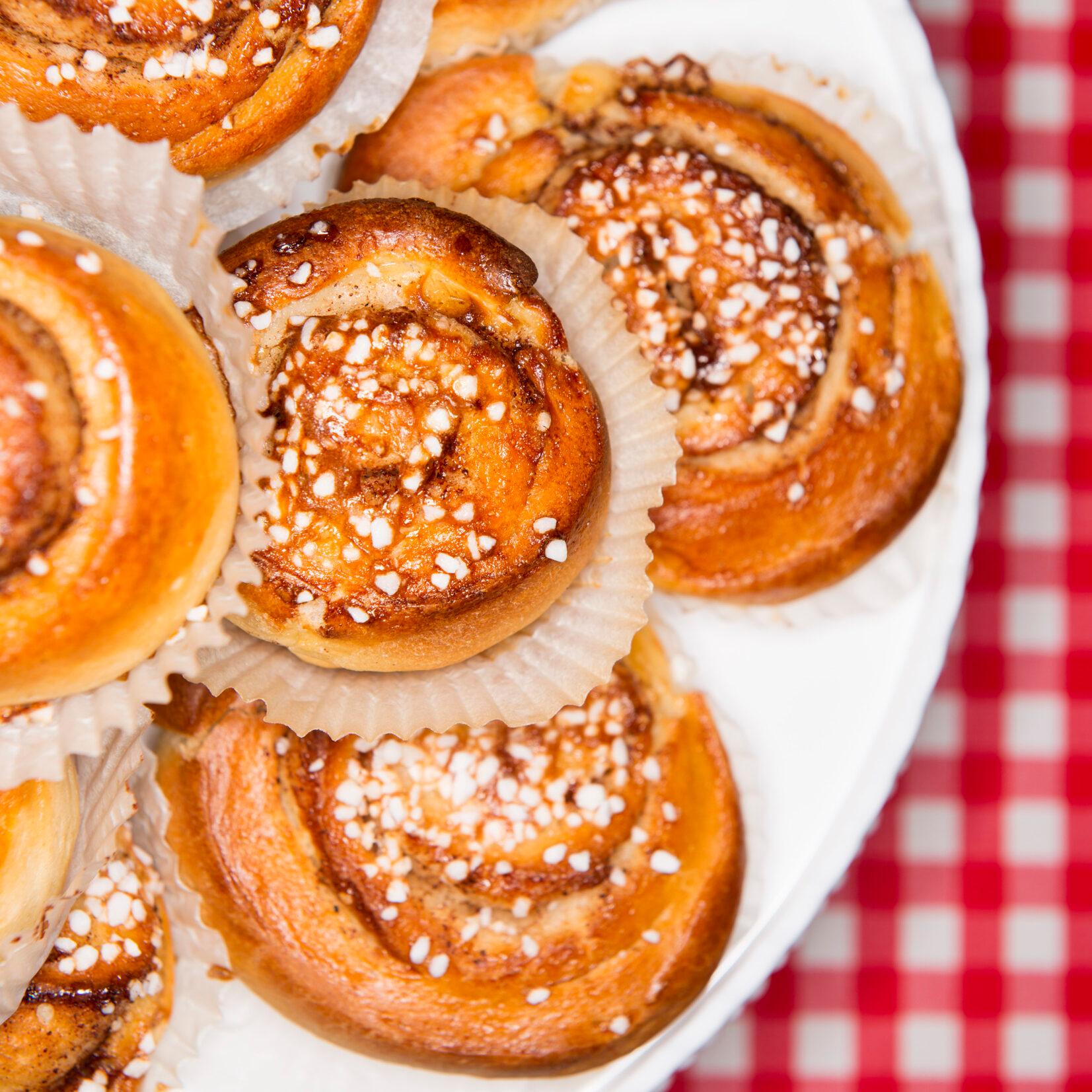 Cinnamon buns Seen from above, a plate filled with cinnamon buns on top of a red and white table cloth.